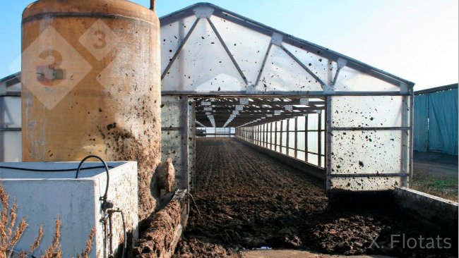 Figura 2. Imagen de sistema de secado solar mediante invernadero. En primer plano se aprecia el dep&oacute;sito de &aacute;cido y un biofiltro para el tratamiento de las emisiones gaseosas (gentileza de J. Soler, EMA depuraci&oacute;, Olot, Gerona).
