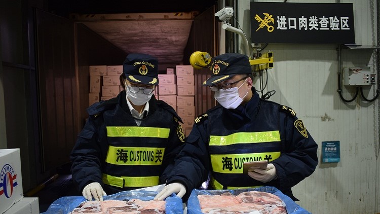 Customs officers inspect imported frozen pork products. Photo credit: Jiang Songqi