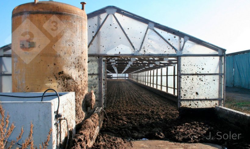 Figure 2. Picture of a solar drying system using a greenhouse. In the foreground is the acid tank and a biofilter for the treatment of gaseous emissions. (Courtesy of J. Soler, EMA depuraci&oacute;, Olot, Gerona)
