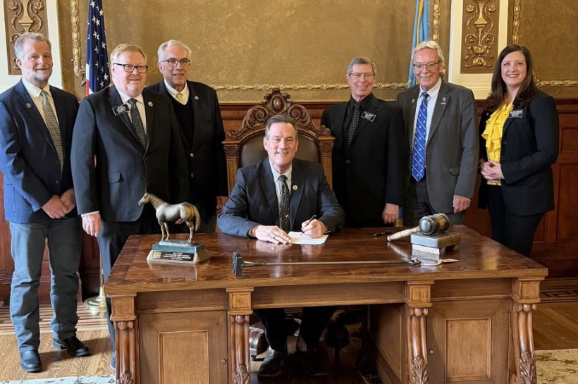 South Dakota State University officials and state lawmakers look on as South Dakota Gov. Larry Rhoden signs a bill Tuesday authorizing the expansion of the SDSU Swine Education and Research Facility.